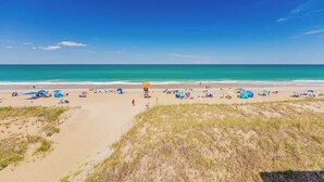 Une plage avec du sable, de l’herbe et un ciel bleu dégagé.