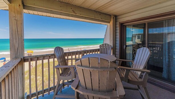 Une terrasse en bois offrant une vue sur la plage et l’océan.