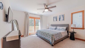 Quarto com cama, ventilador de teto, janela com persianas e porta que dá para área externa.