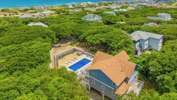 A residential area with houses surrounded by dense greenery, a swimming pool, and a view of the ocean. - JL #034 - Solitude House - Oceanside - Private Pool - Hot Tub (Southern Shores)