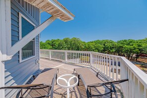 A wooden deck with a white railing, a table, and chairs, overlooking a green landscape. - JL #034 - Solitude House - Oceanside - Private Pool - Hot Tub (Southern Shores)