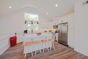 A kitchen with white cabinets, a stainless steel refrigerator, a microwave, and a red trash bin. - JL #034 - Solitude House - Oceanside - Private Pool - Hot Tub (Southern Shores)