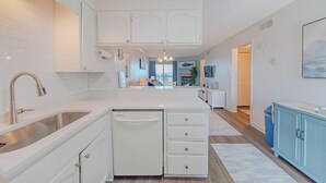 A modern kitchen with white cabinetry, a stainless steel sink, and a built-in dishwasher. - JL #R-10 | The Regency Condominium | Oceanfront | Community Pool (Kill Devil Hills)
