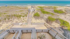 A beach view with a wooden boardwalk leading to a sandy area. - JL #R-10 | The Regency Condominium | Oceanfront | Community Pool (Kill Devil Hills)