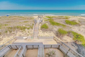 A beach view with a wooden boardwalk leading to a sandy area. - JL #R-10 | The Regency Condominium | Oceanfront | Community Pool (Kill Devil Hills)