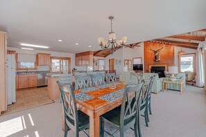 A spacious living area with a dining table, chairs, a fireplace, and a television. - JL #228 | Tengerhaz | Oceanfront | Ocean Views (Duck)