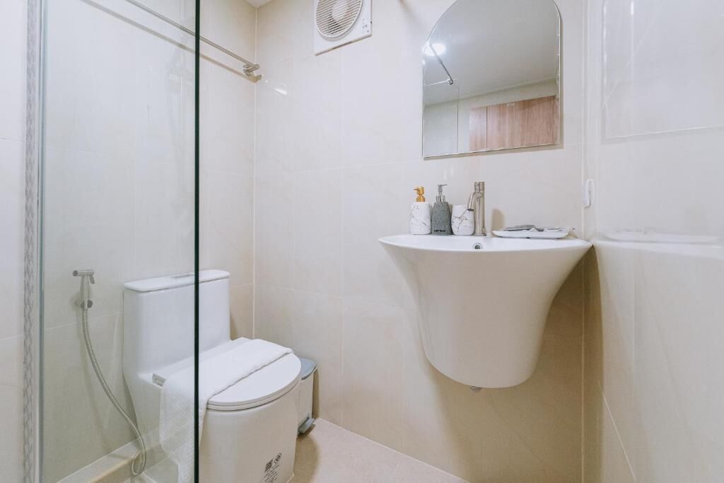 Een badkamer met een douchecabine van glas, een wit wastafelmeubel en een spiegel erboven.