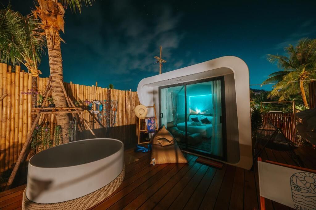 A modern outdoor bathroom with a glass enclosure, a hot tub, and a wooden deck.