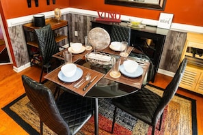 A dining area with a round table set for four, black chairs, and a fireplace in the background. - Gated Atlanta 3BR Gem | Private Community Pool (Atlanta)
