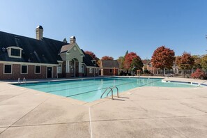 A swimming pool with a brick building in the background. - Gated Atlanta 3BR Gem | Private Community Pool (Atlanta)