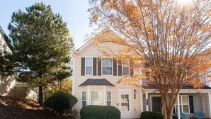 A two-story house with a front porch, a garage, and a driveway.
