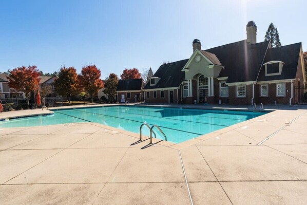 Une piscine à l’eau d’un bleu limpide, entourée d’une terrasse dallée.