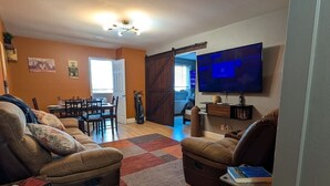 A living room with a sofa, a coffee table, a TV, and a bookshelf. - Downtown Atlanta 3BR Condo • Near Stadium & Arena (Atlanta)