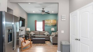A modern living room with a sofa set, a coffee table, a TV, and a water dispenser. - Cozy 4BR with Porch, King Bed Near Mercedez Benz & Downtown, Pet Friendly (Atlanta)