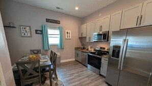 A kitchen with a dining area, a refrigerator, microwave, oven, and a sink. - Cozy 4BR with Porch, King Bed Near Mercedez Benz & Downtown, Pet Friendly (Atlanta)