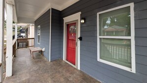 A covered porch with a red door, a bench, and a window with a white frame. - Cozy 4BR with Porch, King Bed Near Mercedez Benz & Downtown, Pet Friendly (Atlanta)