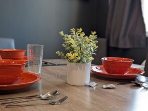 A dining table with red bowls, a white vase with yellow flowers, and a clear glass. - Urban Comfort | King Beds & Movie Nights (Atlanta)