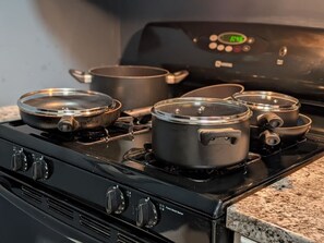 A kitchen with a stove, pots, and a digital clock. - Urban Comfort | King Beds & Movie Nights (Atlanta)