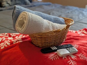 A wicker basket with rolled towels and two remote controls on a red blanket. - 2BR Urban Comfort 2 King Beds & Movie Nights (Atlanta)