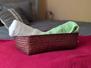 A woven basket with a green towel on a red textured surface. - 2BR Urban Comfort 2 King Beds & Movie Nights (Atlanta)