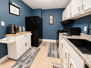 A kitchen with a black refrigerator, white cabinets, a granite countertop, and a black stove. - Urban Comfort | King Beds & Movie Nights (Atlanta)