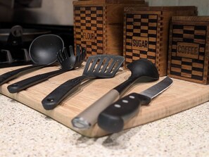 Uma bancada de cozinha com utensílios diversos e recipientes de madeira identificados com 'FLOUR', 'SUGAR' e 'COFFEE'.
