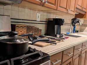 Uma cozinha com fogão, cafeteira e diversos utensílios sobre a bancada.