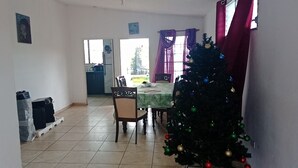 Ein Essbereich mit einem Weihnachtsbaum, einem Tisch mit grüner Tischdecke und Stühlen.