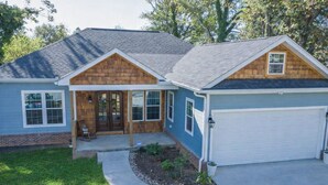 Ein zweistöckiges Haus mit Garage, Veranda und einem angelegten Vorgarten.