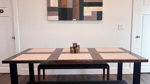 Ein Zimmer mit einem langen Holztisch, einer Bank und einem Wandbild.