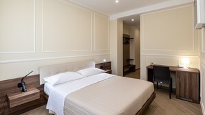 A hotel room with a bed, bedside table, desk, chair, and a mirror. - Scaligero Rooms Ida - Tosca - Rigoletto (Verona)