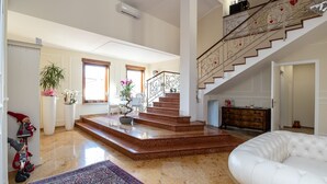 A spacious living area with a staircase, a white sofa, and a potted plant. - Scaligero Rooms Ida - Tosca - Rigoletto (Verona)