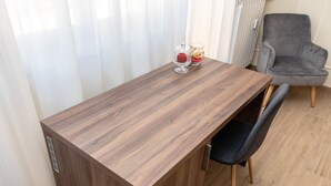 A wooden dining table with a chair, a glass container with a red object, and a grey armchair. - Scaligero Rooms Romeo (Verona)