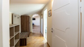 A hallway with a built-in bench, a white door, and a view into a room with a toilet and a chair. - Scaligero Rooms Romeo (Verona)