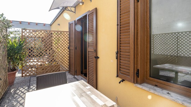 Un espace patio avec une table, des volets en bois et une plante en pot.