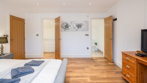 A bedroom with a bed, wooden wardrobe, and a TV stand. - Beautiful Eco Barn - sleeping 10 (Staveley)