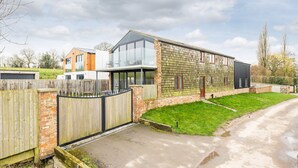 A modern two-story house with a large glass balcony, a brick exterior, and a wooden fence. - Beautiful Eco Barn - sleeping 10 (Staveley)