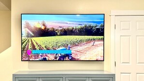 Un téléviseur fixé au mur affiche une scène de vignoble avec un tracteur.