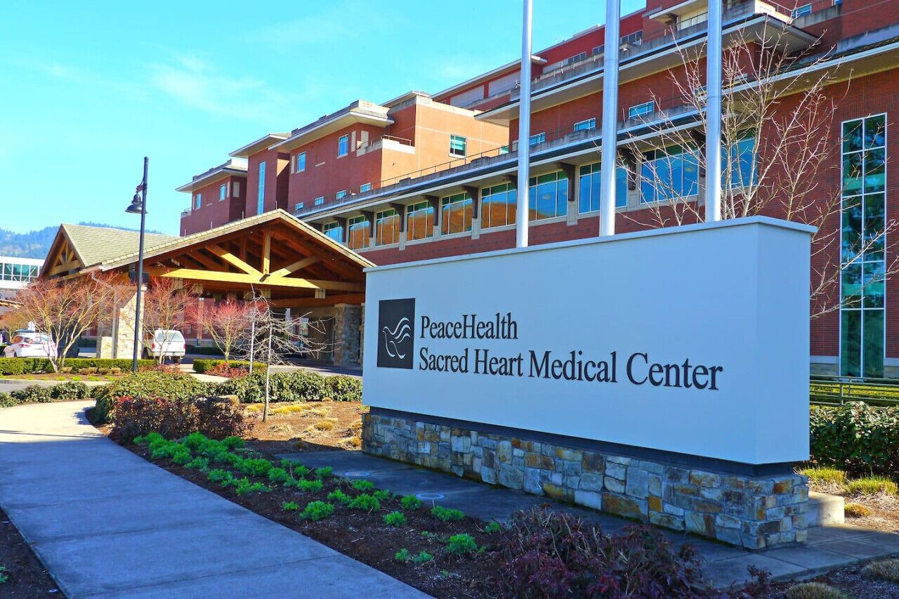 A medical center with a sign reading 'PeaceHealth Sacred Heart Medical Center.'