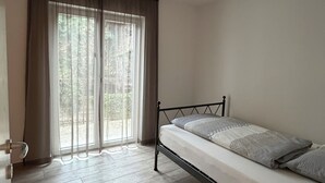 Una habitación con cama, puerta y ventana con cortinas.