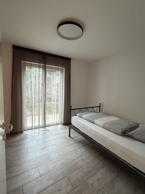 Ein Zimmer mit einem Bett, einer Tür und einem Fenster mit Vorhängen.