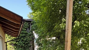 Un espacio de estar al aire libre techado con un sofá, sillas, una mesa y una estructura de pérgola.