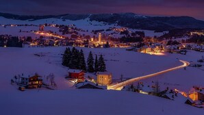 A snow-covered village with illuminated buildings and a winding road. - Piccali House: Ground Floor Apartment in the heart of ROANA (Roana)