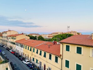 A row of buildings with red-tiled roofs and green shutters, a clear sky, and a crescent moon. - Five minutes from the sea. Very bright with east south west windows Art and Design (Livorno)
