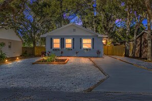 A single-story house with a gravel driveway, a wooden fence, and a well-maintained lawn. - NEW Saltwater Pool 3br near the beach! (Clearwater)