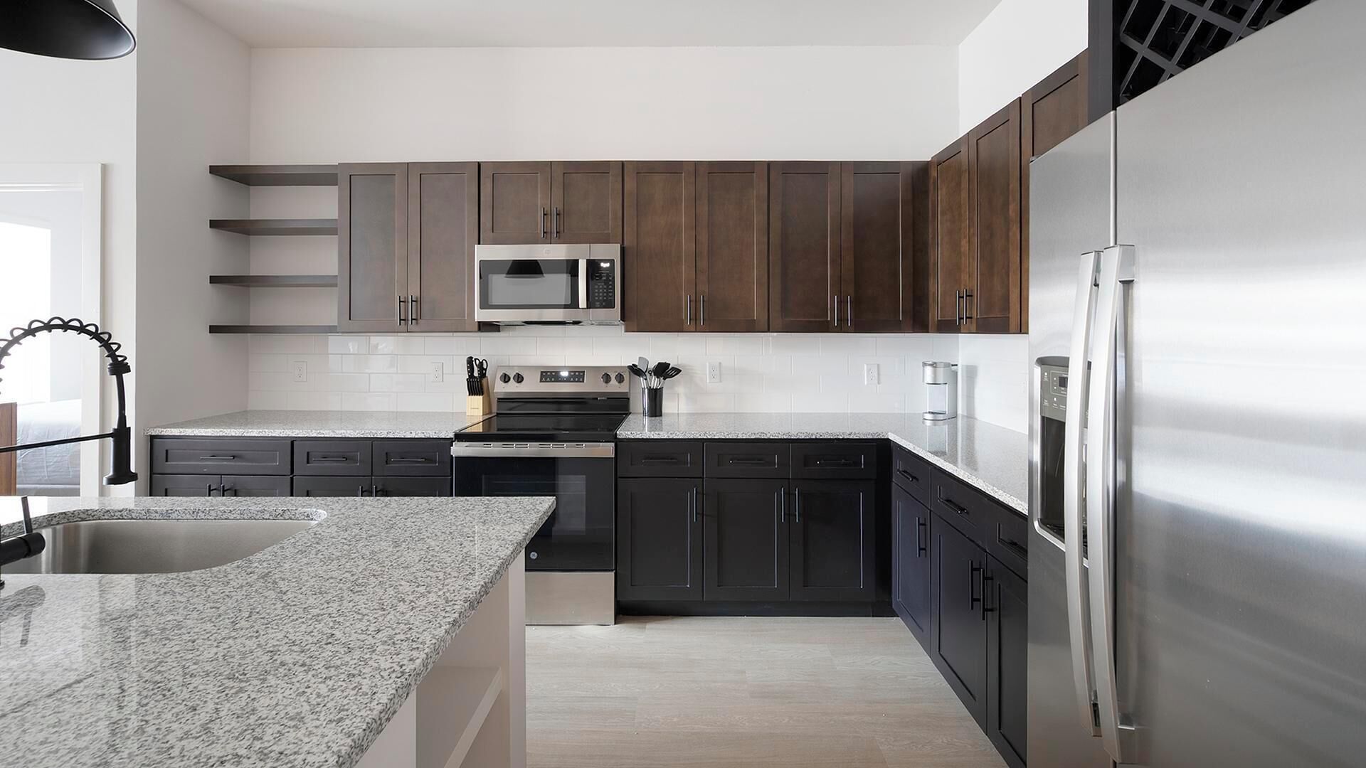 A modern kitchen with dark wooden cabinets, stainless steel appliances, and a granite countertop.