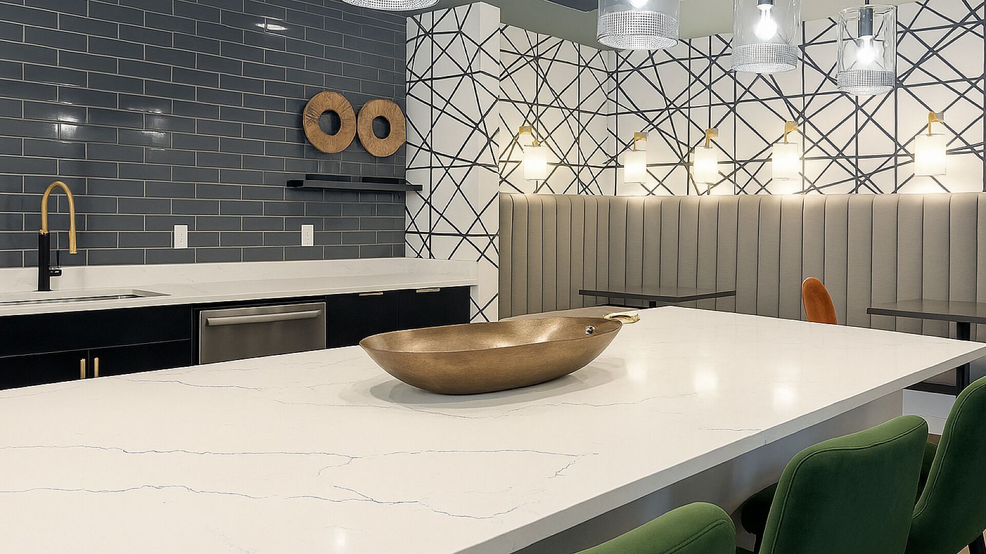 Uma cozinha moderna com uma ilha grande, painel de backsplash preto e branco e iluminação pendente.