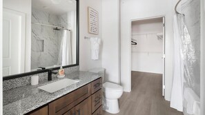 A bathroom with a marble sink, a toilet, a shower curtain, and a towel rack. - Landing | Modern 1BD, Yoga Studio, Clubhouse (Little Rock)