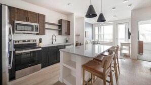 Una cocina moderna con gabinetes oscuros, electrodomésticos de acero inoxidable y una isla central con taburetes de bar.