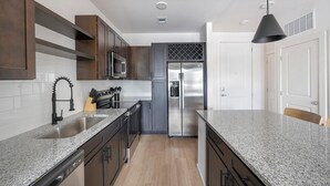 A modern kitchen with granite countertops, stainless steel appliances, and dark wood cabinetry. - Landing | Spectacular 1BD, Clubhouse, Yoga Studio (Little Rock)